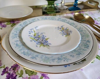 May include: Three white ceramic plates with a blue and white floral pattern. The plates are stacked on top of each other and have a gold rim.