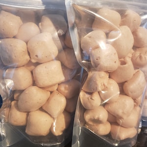 May include: Two clear plastic bags filled with small, light brown, irregularly shaped, chewy candies.