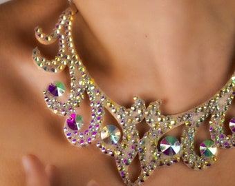 Puede incluir: Un delicado collar adornado con cristales transparentes y brillantes. El collar tiene forma de diseño floral estilizado y un acabado brillante e iridiscente.