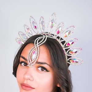 May include: A silver and crystal headpiece with a teardrop design. The headpiece is adorned with iridescent crystals and has a delicate, feminine look.