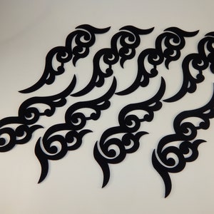 Può includere: Un set di 10 sagome di carta nere a forma di nuvole stilizzate. Le nuvole sono intricate e dettagliate, con motivi a spirale.