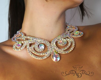 May include: A delicate, cream-colored rhinestone necklace with a teardrop-shaped pendant. The necklace features a swirling, ornate design with clear rhinestones.