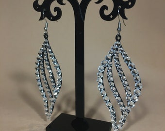 May include: A pair of silver dangle earrings with a teardrop shape. The earrings are made of multiple rows of clear rhinestones.