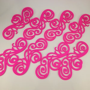 May include: A set of nine pink paper cut-outs in a swirling, floral design. The cut-outs are intricate and delicate, with a variety of shapes and sizes.