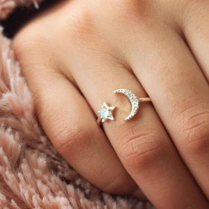 May include: A gold ring with a crescent moon and a star design. The ring is set with small clear stones.