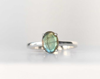 May include: A silver ring featuring a green oval-shaped labradorite gemstone.