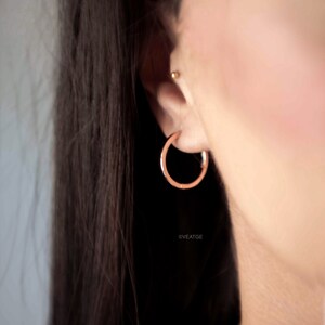 May include: A pair of rose gold hoop earrings. The earrings are simple and elegant, and they would make a great gift for any occasion.