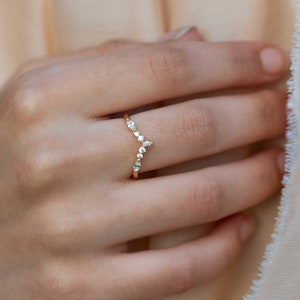 May include: A delicate gold ring with a V-shaped band of small diamonds.