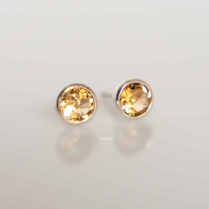 May include: A pair of silver stud earrings with round, light brown gemstones.