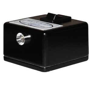 May include: A black rectangular Gem-A Instruments sodium line refractometer lamp with a silver circular lens on the front face and a black rocker switch on the top surface. A white label with black text is affixed to the top of the device.