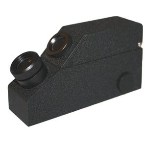 May include: A black, textured, rectangular optical device featuring two circular lenses positioned at an angle on the top surface. The device has a solid, elongated body with a matte finish and a small circular button located on the side panel.