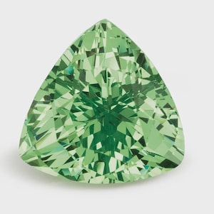 Può includere: Una pietra preziosa dal taglio triangolare di un vibrante colore verde chiaro con una superficie sfaccettata che crea un complesso motivo di riflessi geometrici. La pietra presenta bordi netti e una punta superiore molto brillante.