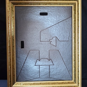 May include: A rectangular picture frame with a metallic gold finish featuring a textured, mottled pattern. The back of the frame is covered by a dark brown, textured cardboard backing panel that includes a rectangular cutout and a stand mechanism.