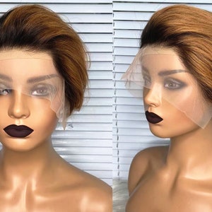 Könnte beinhalten: Eine kurze, braune und blonde Perücke mit einem Spitzenfront. Die Perücke befindet sich auf einem Mannequin-Kopf.