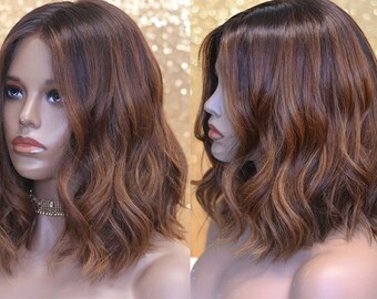 May include: A brown and blonde wavy bob wig with a lace front. The wig is styled with loose waves and has a natural-looking hairline.