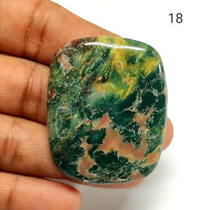 May include: A polished, rectangular-shaped gemstone with rounded corners, featuring a marbled pattern of deep forest green, vibrant yellow, and soft peach-colored inclusions. The stone has a smooth, glossy surface and is marked with the number 18.