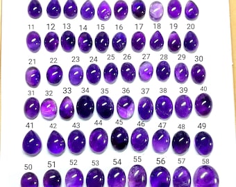 Könnte beinhalten: Eine Sammlung von 58 polierten Amethyst-Edelsteinen, jede mit einer einzigartigen Form und einem einzigartigen Farbton von Lila. Die Edelsteine sind von 1 bis 58 nummeriert und auf einer weißen Oberfläche in Reihen und Spalten angeordnet. Die Edelsteine variieren in Größe und Klarheit.