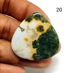 May include: A polished, triangular-shaped gemstone cabochon featuring a mix of white, deep forest green, and mustard yellow patterns. The stone has a smooth, glossy surface with distinct color zones and the number 20 printed in the upper right corner.