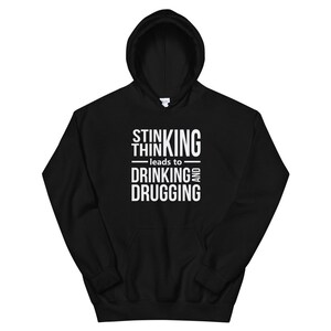 May include: Black hoodie with the white text "STINKING THINKING leads to DRINKING AND DRUGGING". The sweatshirt features a hood with a drawstring and a front pocket. A casual, comfortable garment.