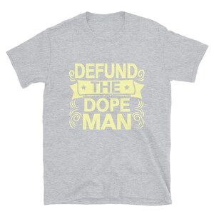 Peut inclure: Un t-shirt gris &agrave; manches courtes avec le texte "DEFUND THE DOPE MAN" en jaune.