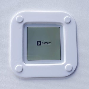May include: White square-shaped device with rounded corners and four white buttons. The device has a black screen with the text "sumup" in white.