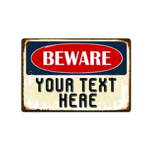 May include: A vintage-style metal sign with a blue and white background. The sign has a red oval with the word "BEWARE" in white letters. Below the oval is the text "YOUR TEXT HERE" in black letters.