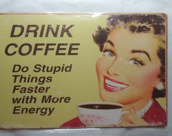 Peut inclure: Une pancarte en métal jaune et marron avec une illustration rétro d'une femme buvant du café. La pancarte indique "Drink Coffee Do Stupid Things Faster with More Energy".