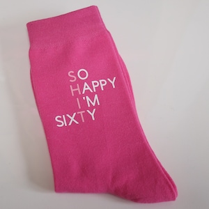 May include: Pink socks with the text "SO HAPPY I'M SIXTY" printed on them.