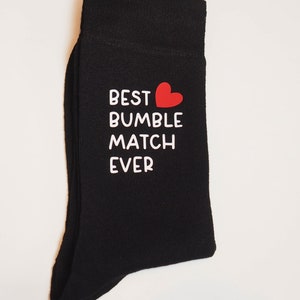 May include: Black socks with white text that reads "BEST BUMBLE MATCH EVER" and a red heart.