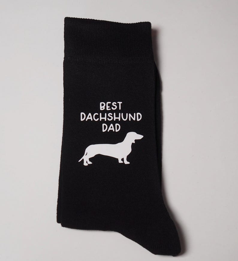 May include: Black socks with a white dachshund silhouette and the text "BEST DACHSHUND DAD" printed on them.