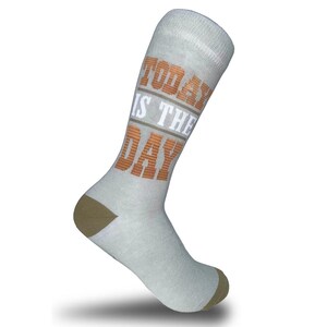 May include: A light grey crew sock featuring the text "TODAY IS THE DAY" printed in a combination of orange and white block lettering. The sock includes a solid brown heel and toe section, with a ribbed cuff at the top for a secure fit.
