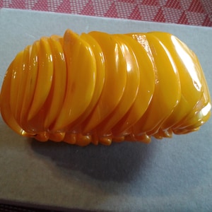 May include: A yellow plastic bracelet made of multiple overlapping pieces, resembling a segmented worm.