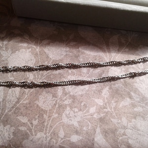 May include: A silver chain necklace with a lobster clasp.