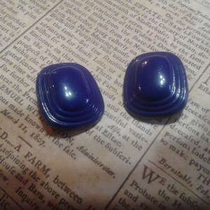 May include: A pair of blue, layered, square-shaped earrings. The earrings have a glossy finish.
