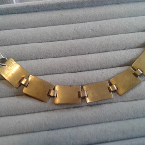 May include: A gold-toned bracelet with square links. The bracelet is made of metal and has a clasp closure.