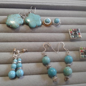 May include: A set of turquoise earrings with different styles. One pair features flower-shaped turquoise stones, another pair has round turquoise beads, and a third pair has a single turquoise stone. There are also two small turquoise studs and two square-shaped turquoise brooches.