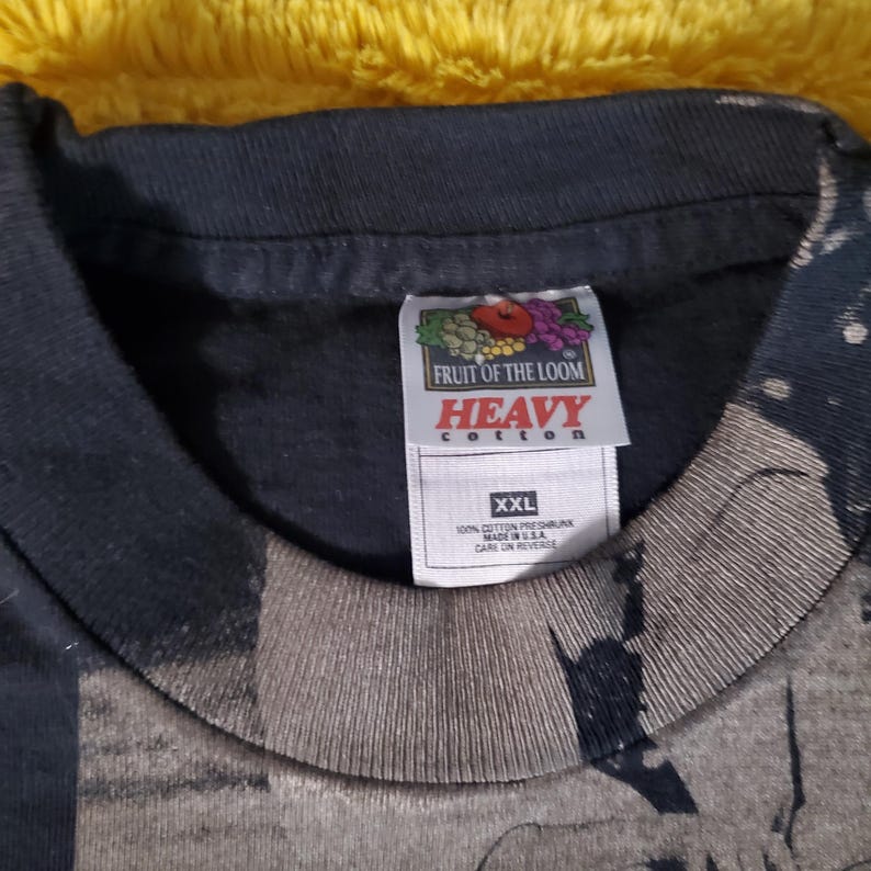 K&ouml;nnte beinhalten: Ein schwarzes Fruit of the Loom Heavy Cotton T-Shirt, Gr&ouml;&szlig;e XXL. Das Etikett zeigt das Markenlogo und den Text. Das Shirt besteht aus 100% Baumwolle und wurde in den USA hergestellt. Das Shirt hat ein verblasstes Design.
