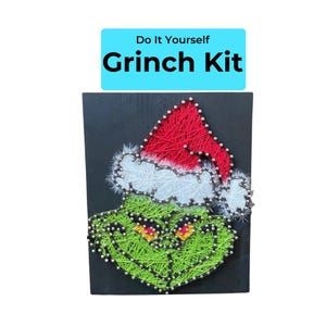 May include: A DIY Grinch Kit on a black wooden board. The Grinch's face is crafted with green string, featuring a red and white Santa hat. The text "Do It Yourself Grinch Kit" is displayed above the image.