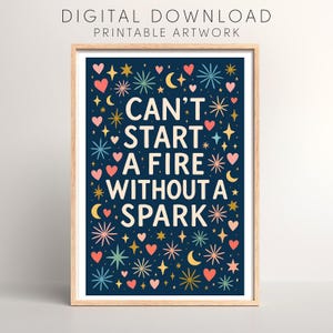 May include: A framed print with a navy blue background and a whimsical design of hearts, stars, and moons. The text "CAN'T START A FIRE WITHOUT A SPARK" is in the center. The words "DIGITAL DOWNLOAD PRINTABLE ARTWORK" are at the top.