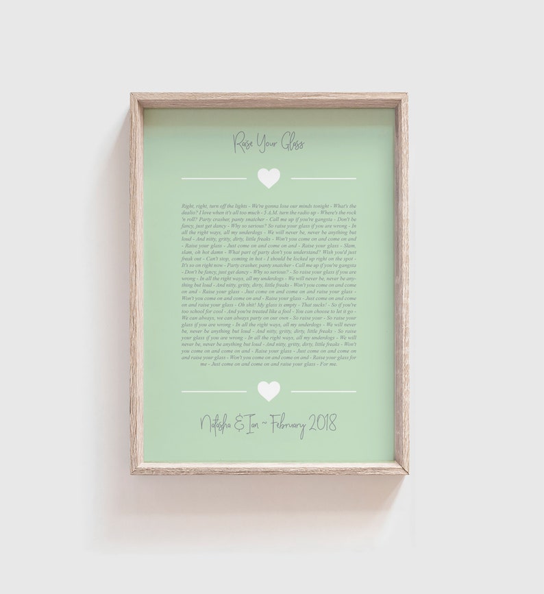 May include: A light green printable art print with a white heart and the text "Raise Your Glass" in a white font. The text continues with a song lyric about raising a glass to celebrate. The print also includes the text "Natasha & Ian - February 2018".