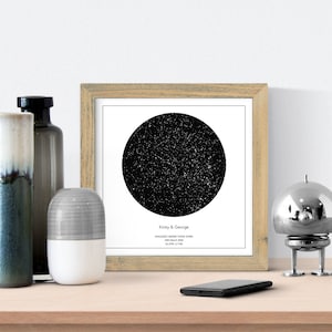 May include: A framed black and white star map print with the text "Kirsty & George" and "Engaged under these stars 8th March 2020 52.2010 0.1210".