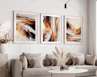 May include: Three abstract paintings featuring orange, brown, and white brushstrokes. The paintings are framed in a simple, modern style and are hung on a white wall.