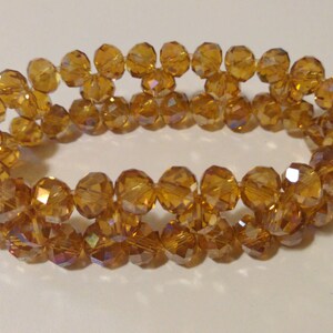 Peut inclure: Un bracelet à double rang de perles en verre de couleur ambre. Les perles sont facettées et ont un léger reflet iridescent.