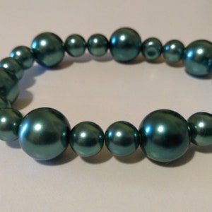 May include: A teal blue pearl bracelet with a stretchy elastic band.