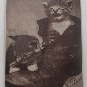 May include: Vintage sepia-toned postcard featuring two kittens. One kitten is inside a large boot, with the name "Max" written on the boot. The other kitten is next to the boot. The text "I Want My Ma" is at the bottom.