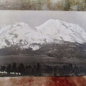 May include: A black and white vintage postcard featuring a snowy mountain range with the text "Mt. Shasta. 593. Pat. R." at the bottom.
