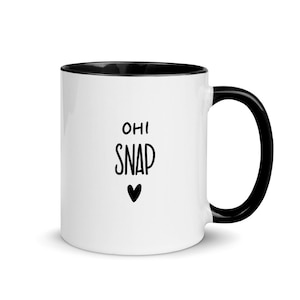 Puede incluir: Taza de café de cerámica blanca con borde y asa negros. La taza tiene texto negro que dice "OH! SNAP" con un pequeño corazón negro debajo del texto.