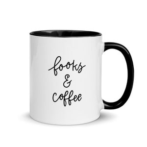 Puede incluir: Taza de café de cerámica blanca con borde y asa negros. La taza tiene texto negro que dice "books & coffee".