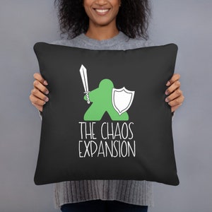 May include: Black throw pillow with a green cartoon figure holding a sword and shield. The text "THE CHAOS EXPANSION" is printed in white below the figure. The pillow is square and appears to be made of a soft fabric.