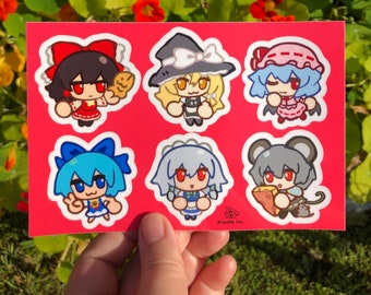May include: A sheet of six colorful stickers featuring cartoon characters from the Touhou Project video game series. The characters are depicted in a chibi style, with large heads and small bodies. The stickers are printed on a white background and have a glossy finish.